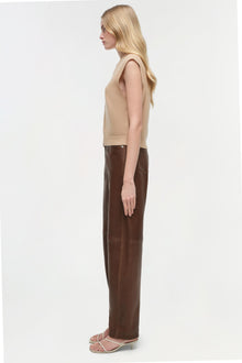 Beige sleeveless cashmere vest on model wearing brown leather pants and strappy heels.