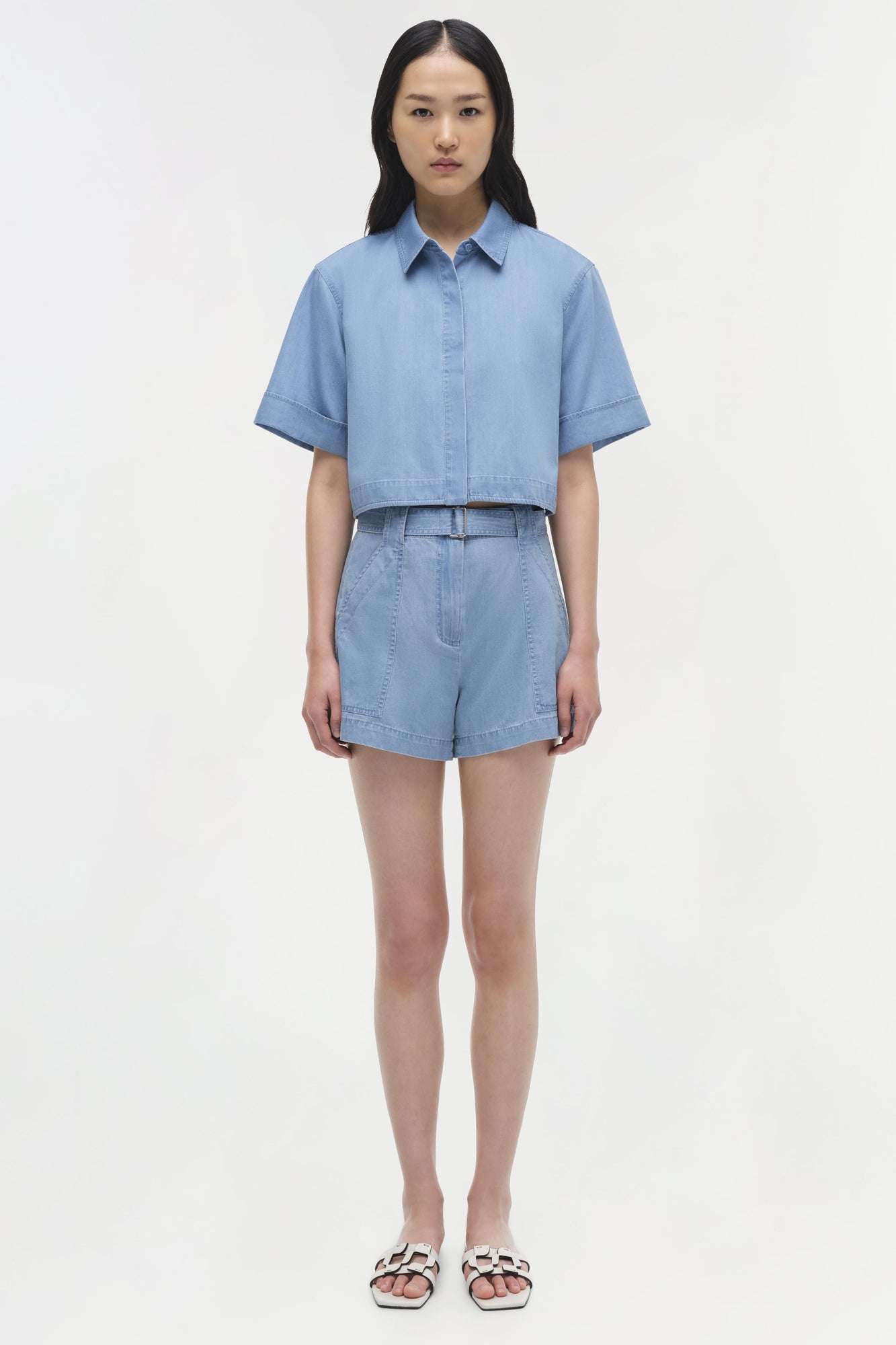 Light blue cropped cotton button-up shirt with short sleeves and collar, displayed on model.