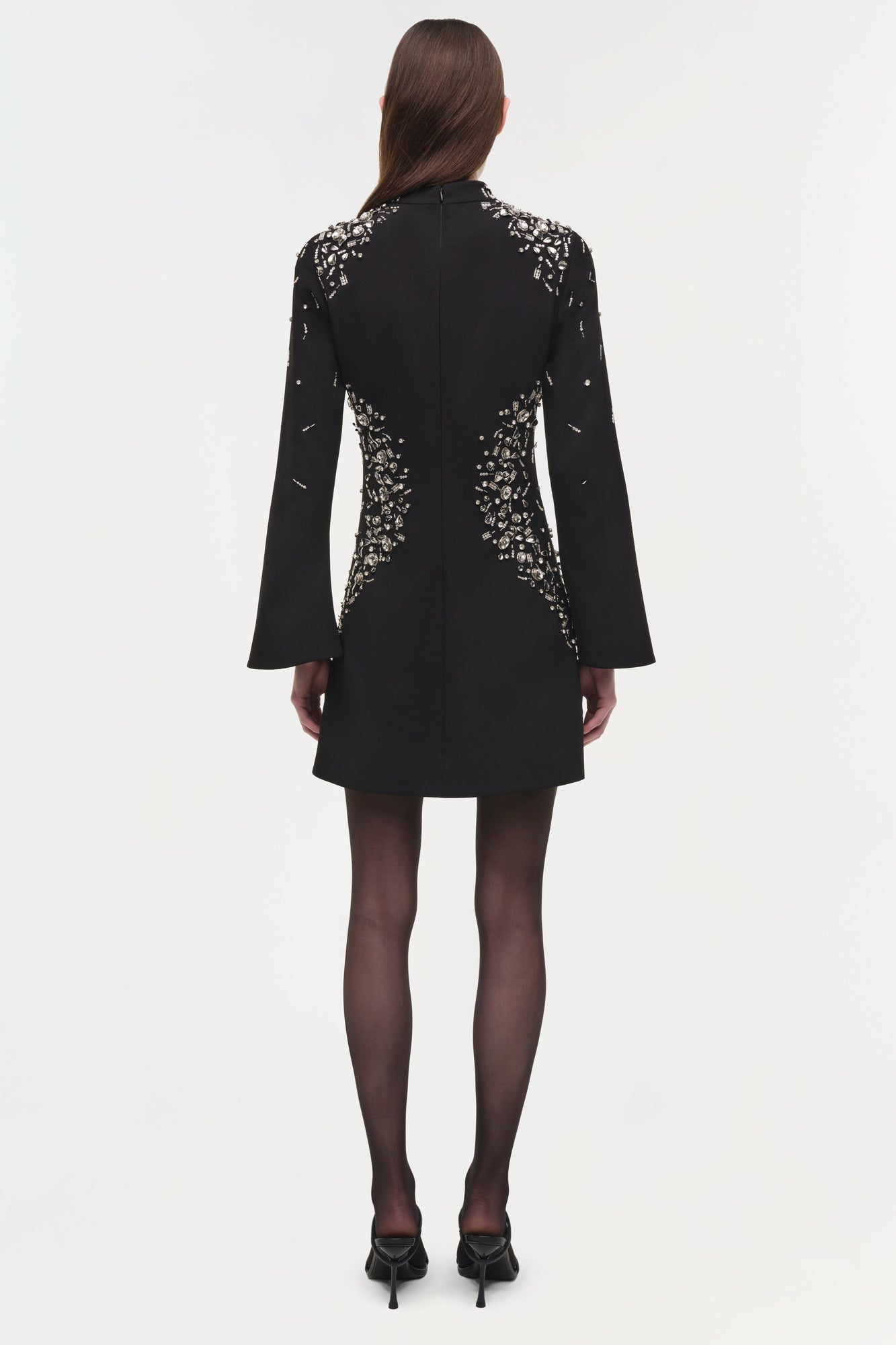 Black mini dress with silver crystal embellishments on shoulders and back, long flared sleeves, worn with dark tights and bla