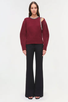 Burgundy ribbed pullover with jeweled neckline and cutout shoulder detail, paired with black flare pants.