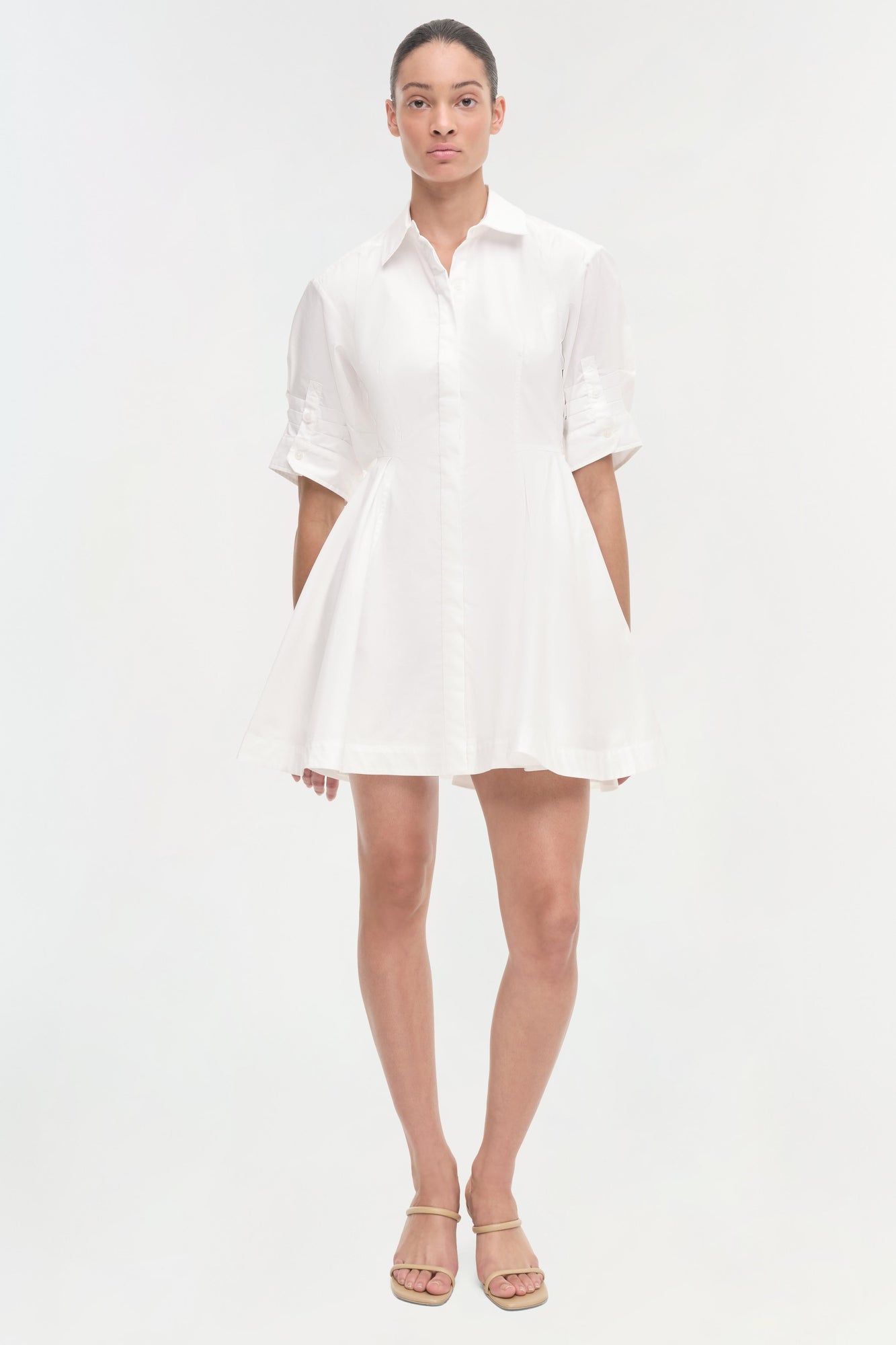 White button-front shirt dress with three-quarter sleeves and a-line skirt, shown on model wearing tan sandals.