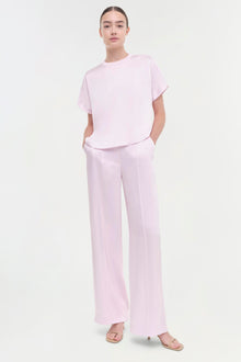 Woman wearing light pink wide-leg pant with front pleats and matching short-sleeve t-shirt.