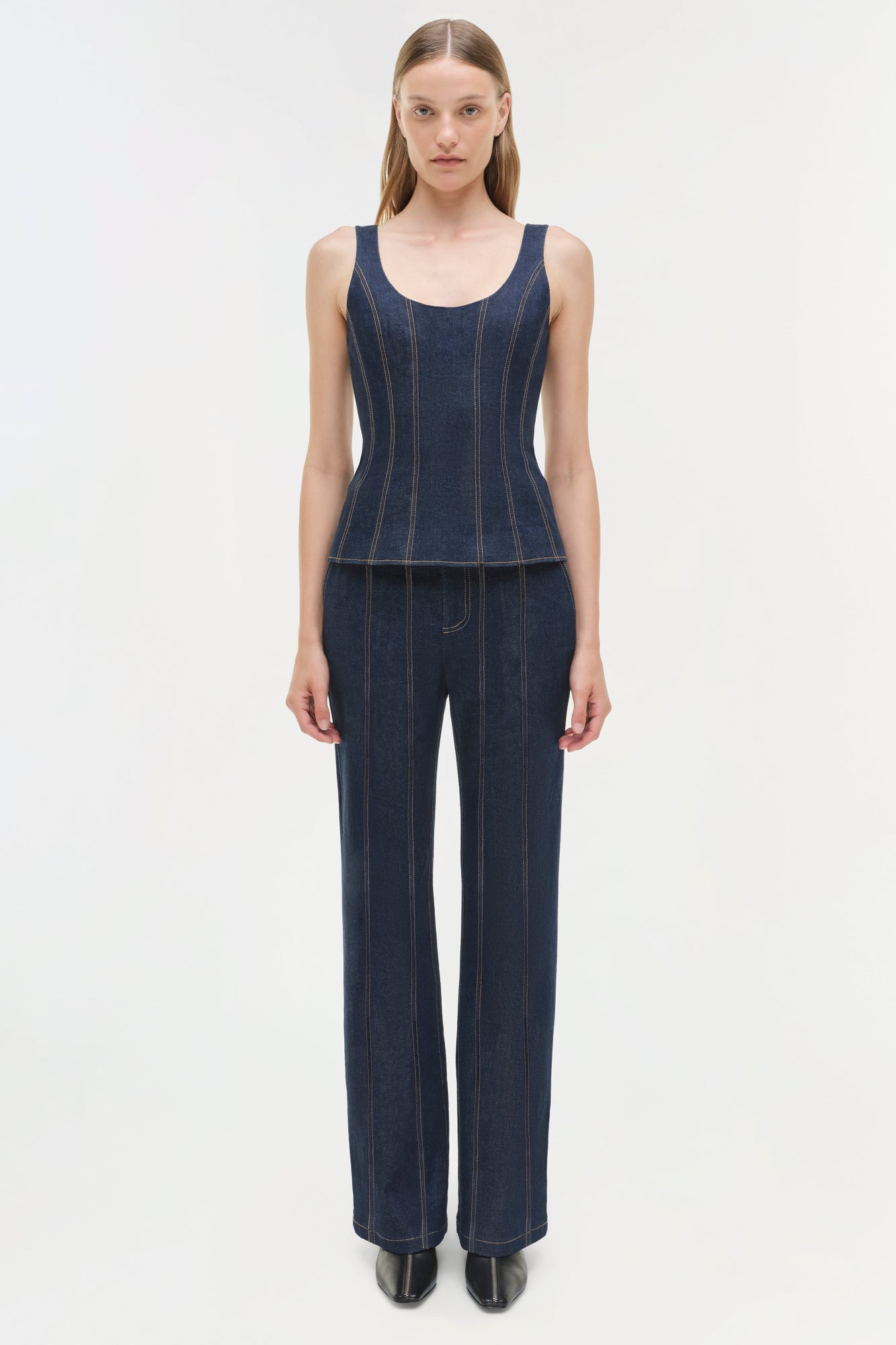 Woman wearing dark blue denim tank top and matching wide-leg trousers with vertical topstitching detail.
