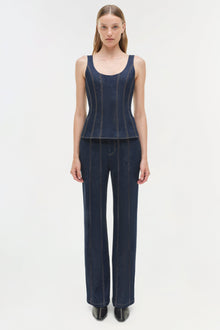 Woman wearing dark blue denim bustier top with vertical stitching and matching wide-leg denim pants.