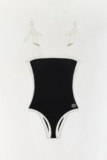 Black and white colorblocked one-piece swimsuit with bow shoulder straps and a small logo on the hip.