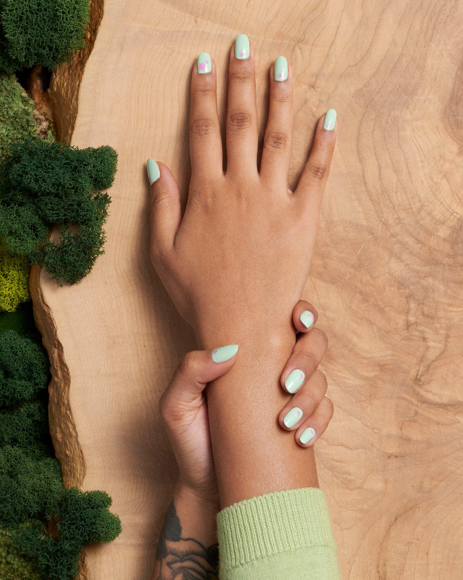 an overhead view of a handing holding a wrist wearing the sprouting polish