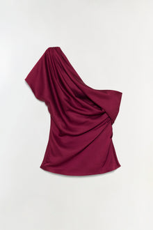 Burgundy satin top with draped one-shoulder neckline and flowing fabric.