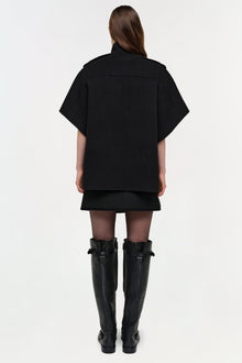 Black wool cape jacket worn over a black dress with knee-high black boots, shown from back view.