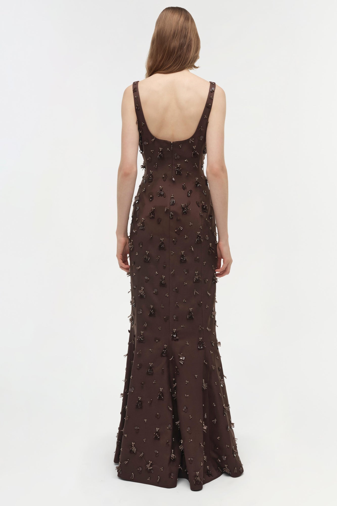 Brown sleeveless gown with beaded embellishments throughout, open back design, worn by model viewed from behind.