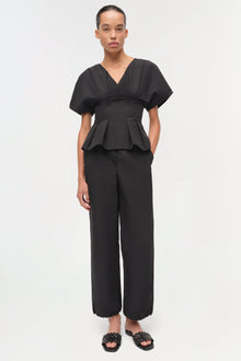 Black cotton faille pull-on pants with wide legs and scalloped hem, shown on model wearing matching peplum top.