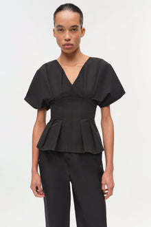 Woman wearing black cotton faille pull-on pants with a matching peplum top.