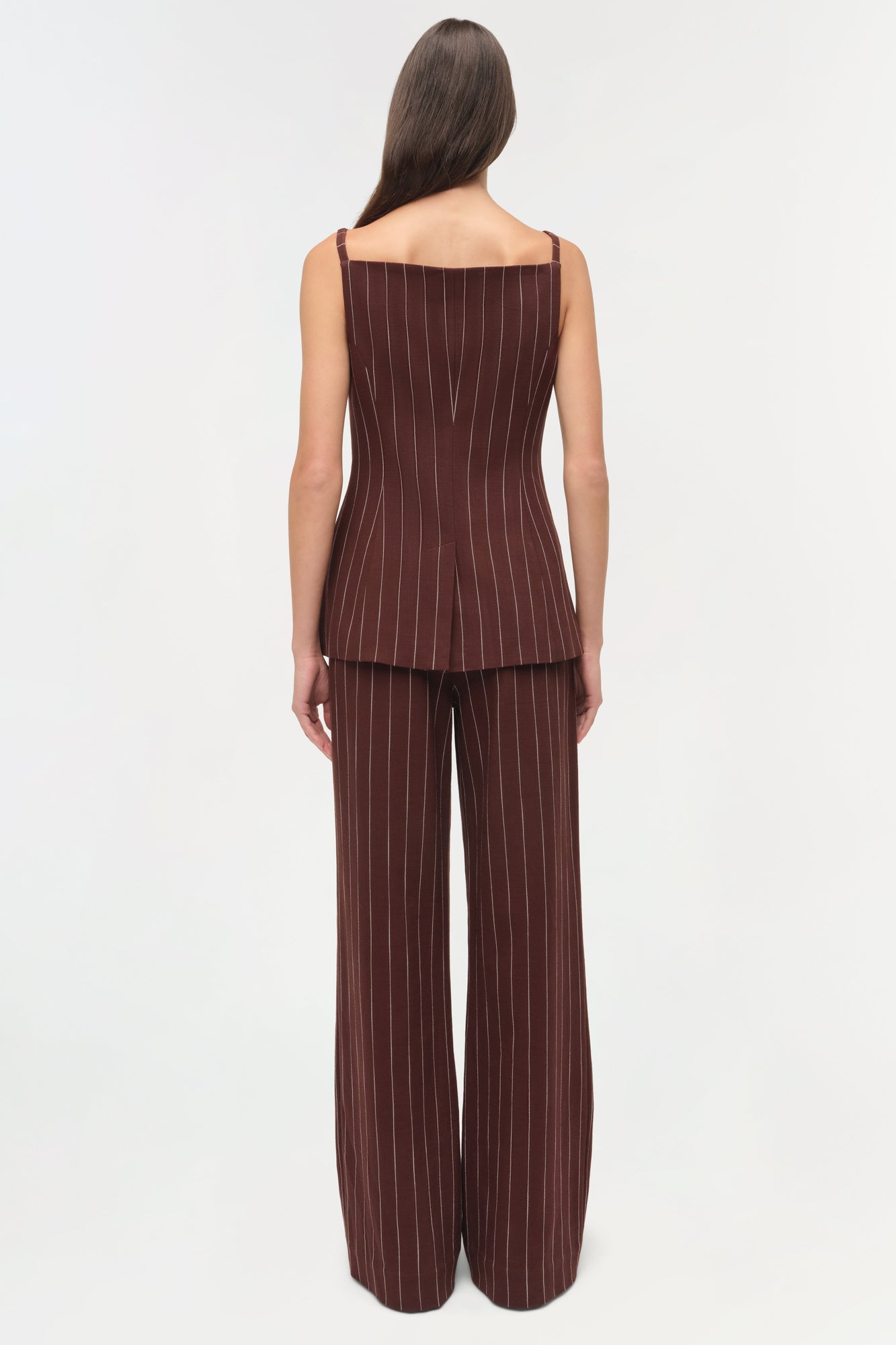 Woman wearing burgundy pinstriped sleeveless top with matching wide-leg pinstriped pants, shown from back view.