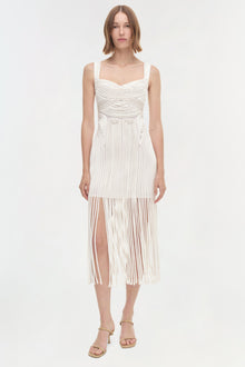 White sleeveless dress with pleated texture, sweetheart neckline, and high slit skirt.