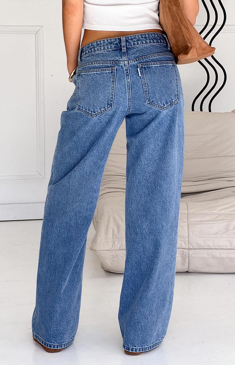Rear view of mid wash blue denim jeans with back pockets, belt loops, and a relaxed straight leg fit