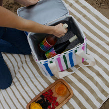 Striped cooler with wine on towel on beach