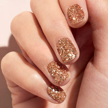 A close-up of fingernails painted with Manucurist’s Glitters Duo Rose Gold  Glazed shows a sparkling, pearlescent shine that catches the light for a festive, glamorous look.