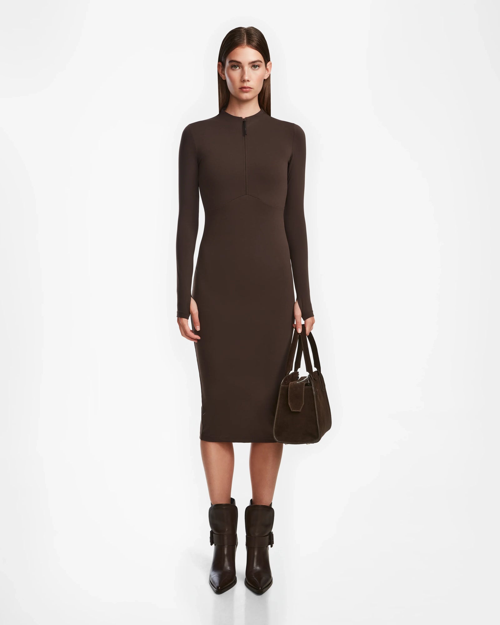 A woman faces forward, wearing the Rudsak AGNES - 8524551 Espresso fitted bodycon dress with long sleeves, paired with brown ankle boots and a brown handbag against a plain white background.