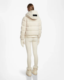 A person faces away wearing the Rudsak DANI S - 8124537 Iceland cream bomber-style ski jacket with hood, matching leggings, gloves, and boots against a plain white background.