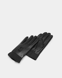 The EDDIE - 6424504 Black gloves by Rudsak, crafted in black leather, are shown stacked on a light gray surface. A subtle embossed logo accents the top glove, offering stylish warmth—the perfect mens winter accessory.