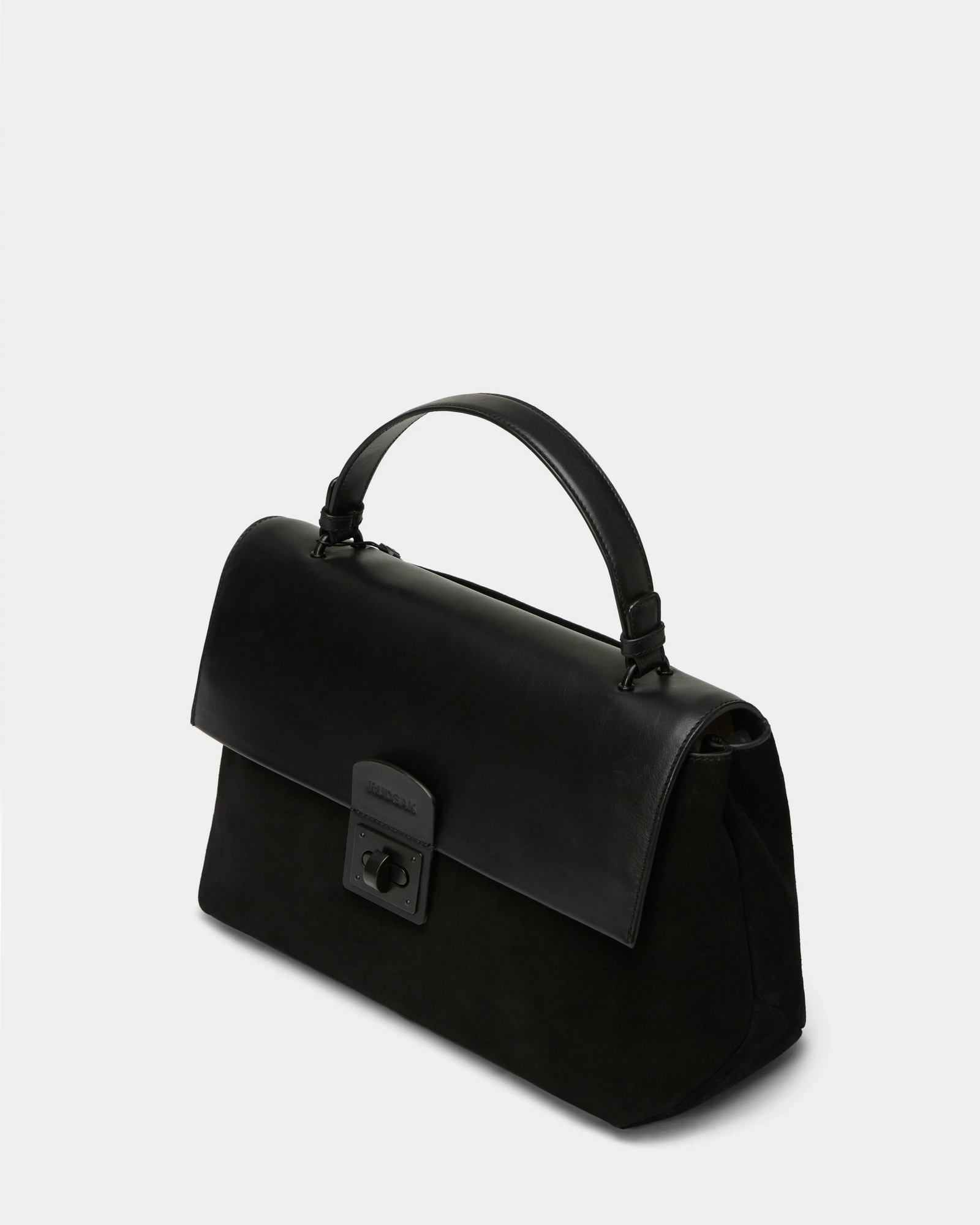The Rudsak ESMA - 8324519 Black is a black suede and leather handbag featuring a top handle, removable shoulder strap, and front clasp closure, shown on a plain light grey background.