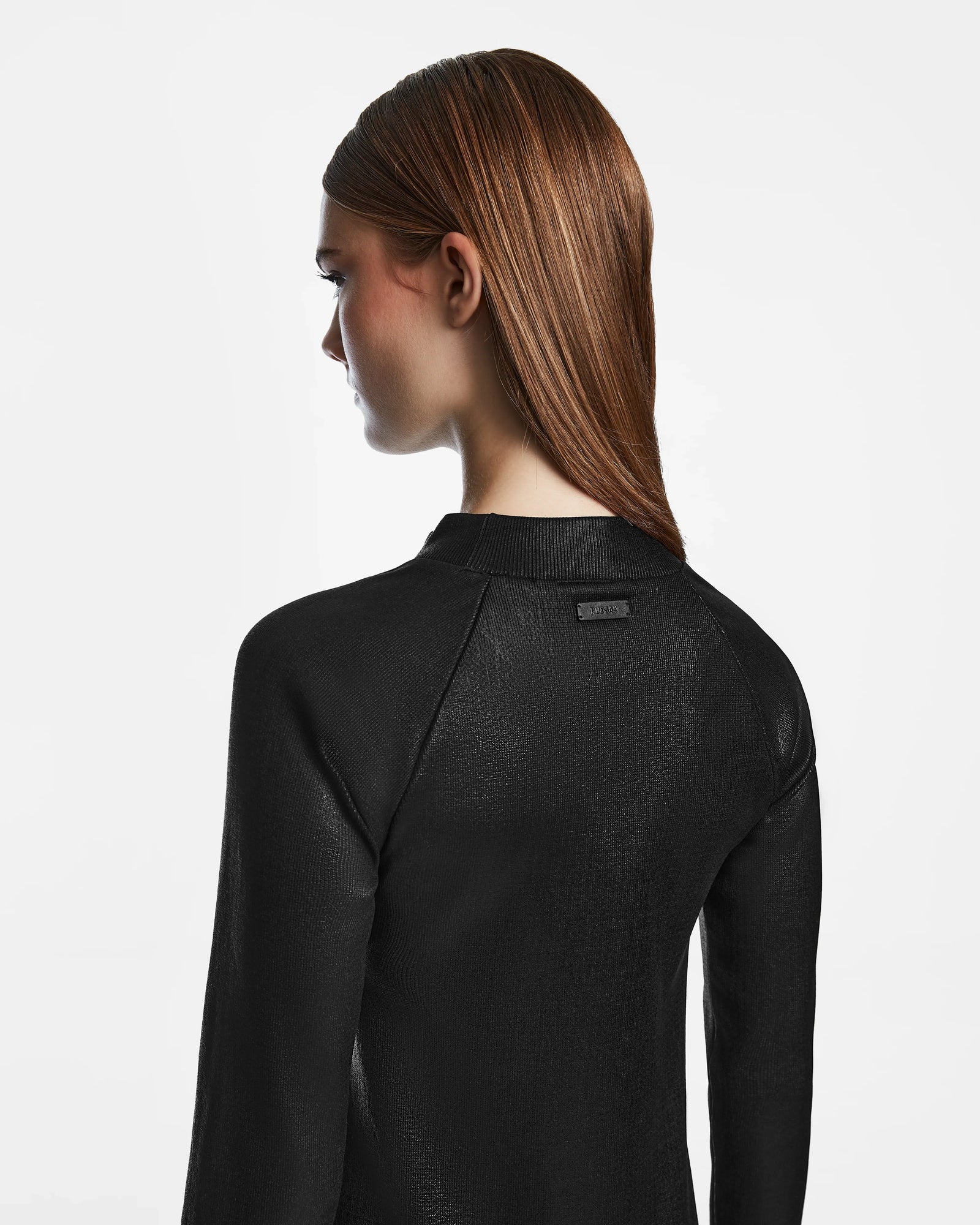 A woman with long, straight brown hair is seen from behind, wearing the Rudsak FAIZA - 8524579 mock-neck dress in textured black against a plain white background.