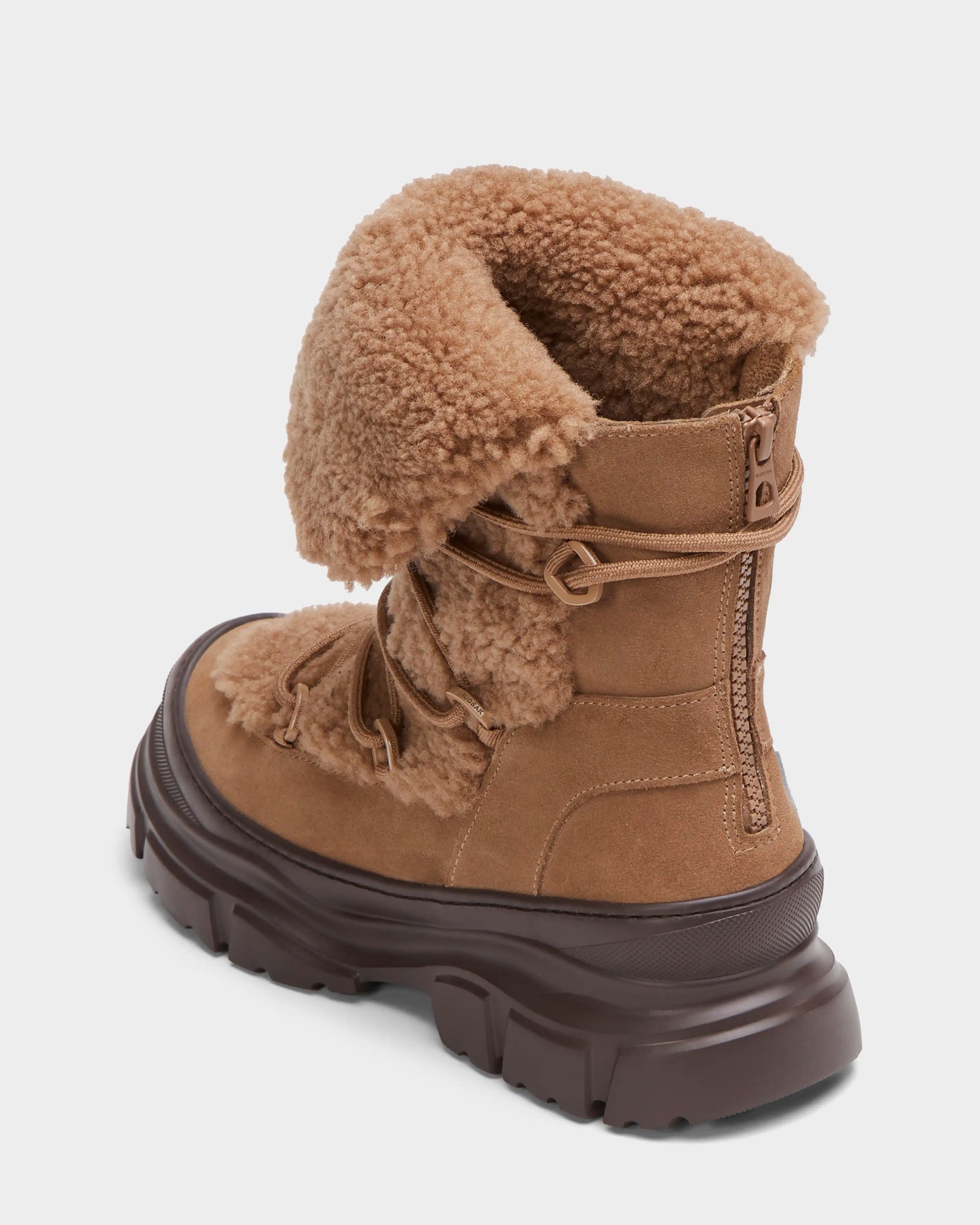The ROKI - 8224533 Camel by Rudsak is a womens winter ankle boot in tan suede with a chunky dark brown sole, lace-up front, side zipper, and a folded shaft that reveals faux shearling lining for added warmth and style.
