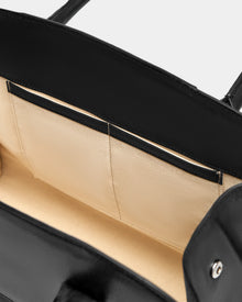 Close-up of the inside of the Rudsak YASMINA L - 8324516 Black leather tote, featuring a beige interior with two flat pockets stitched into the lining.