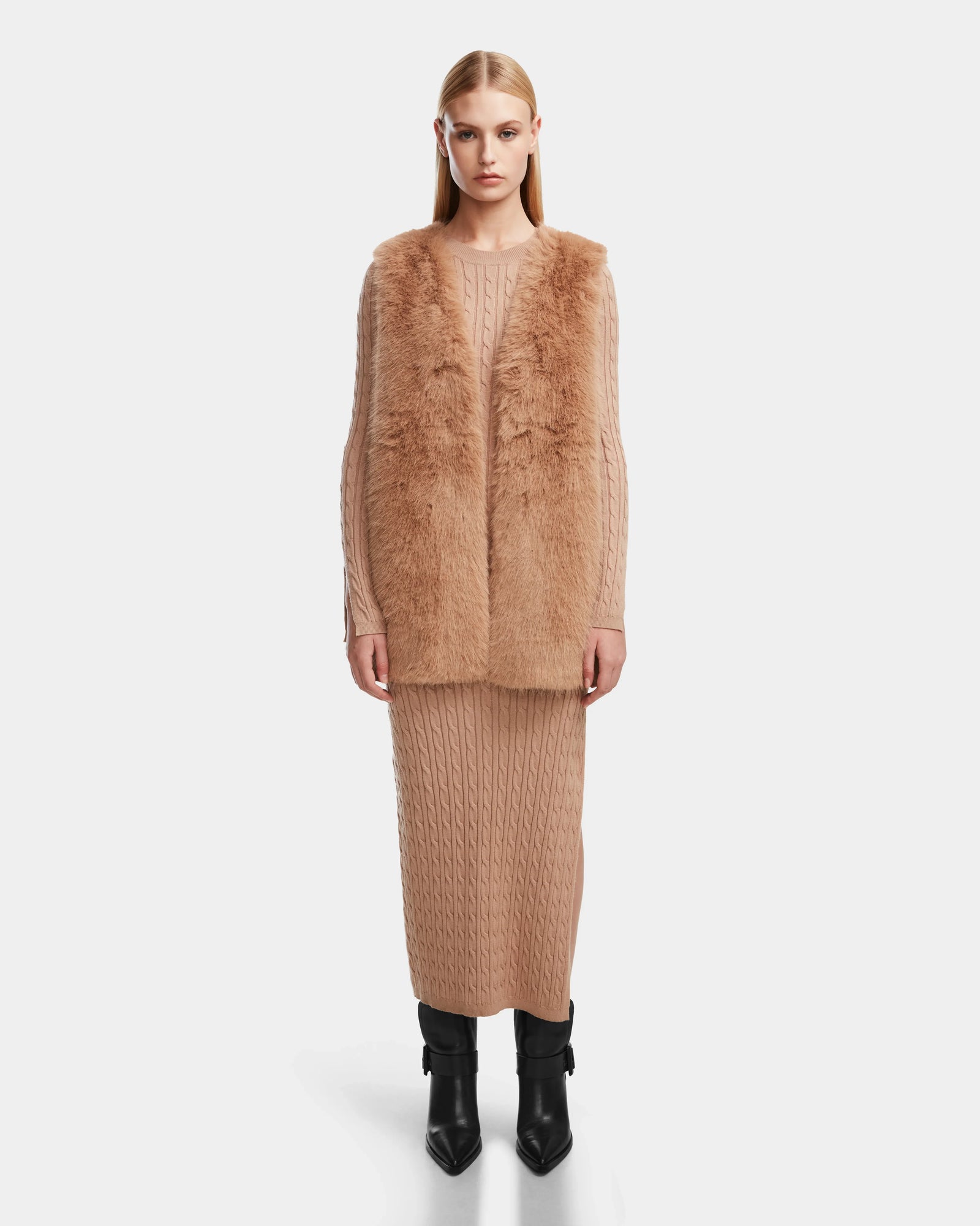 A woman wearing the Rudsak YOLANDA - 8124790 Camel faux fur vest and skirt, cinched with a vegan leather belt—an elegant addition to any fall or winter wardrobe.