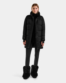 A person stands facing forward wearing the Rudsak ALESSANDRA M - L125552 Black down puffer against a plain white background.