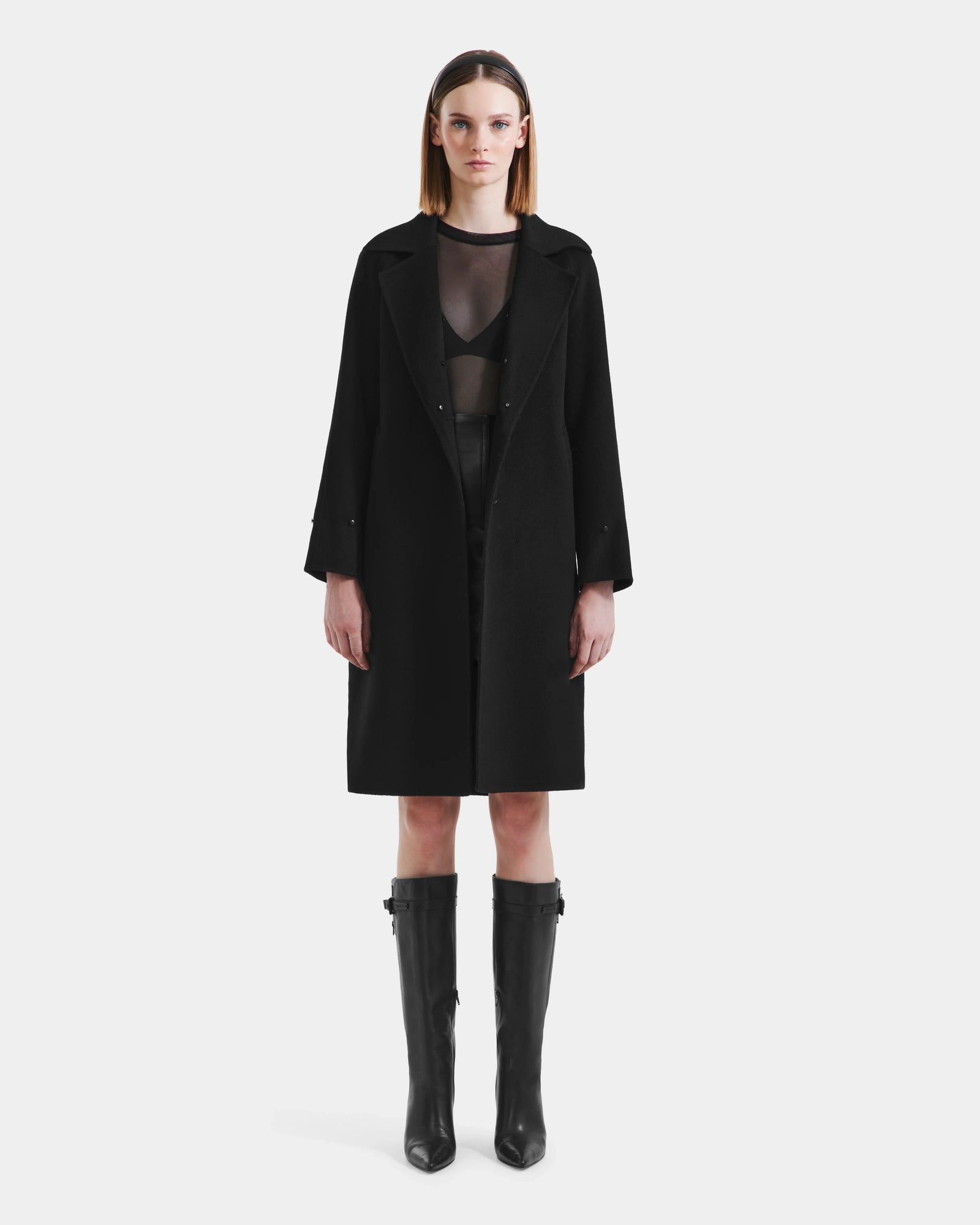 A woman with straight shoulder-length hair and a neutral expression models the Rudsak ARTIS - L125575 Black wool coat with faux fur collar, layered over black pieces, against a plain white background.