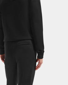Wearing the Rudsak MAXTON - U525007 Black M hoodie and joggers, a person stands against a white background with their back and right arm visible, highlighting everyday comfort and effortless style.