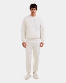A man faces forward in the Rudsak MAXTON - U525007 Vanilla M jogger set—long-sleeve sweatshirt and matching pants with white sneakers—against a plain white background, perfect for everyday comfort.