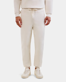 A person wears the Rudsak MAXTON - U525007 Vanilla M jogger pants, shown from the waist down against a white background, highlighting everyday comfort in this cream cotton-blend unisex jogger style.
