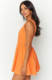 Side view of an orange crinkle mini dress with deep V-neck, sleeveless design, side cutouts, and a ruched elastic waist