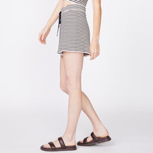 SIde view of model wearing the stripe easy sweater shorts in ivory stripe.