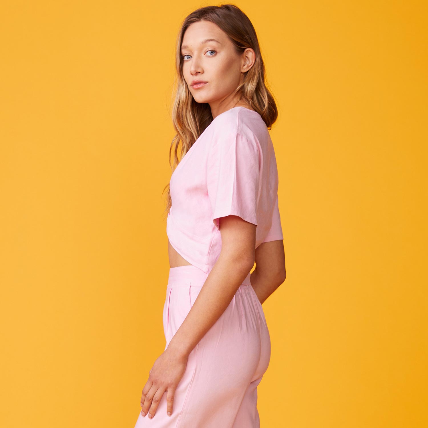 Side view of model wearing the linen front twist top in bubble gum.