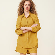 Front view of model wearing the poplin shirt in golden olive.