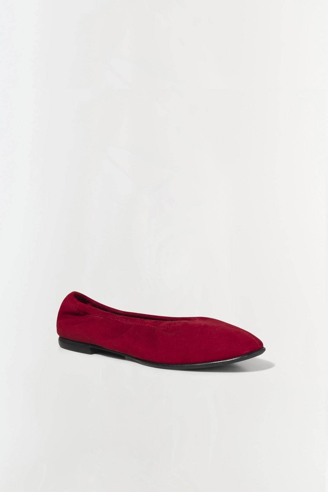 Burgundy suede ballet flat with a black sole, shown in profile view.