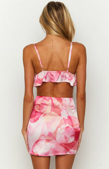 Rear view of a pink satin crop top with a watercolour pattern, thin adjustable spaghetti straps, and a ruffled hem