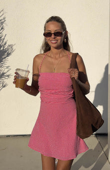 Front view of a red and white gingham mini dress with a ruched bodice and halter neckline