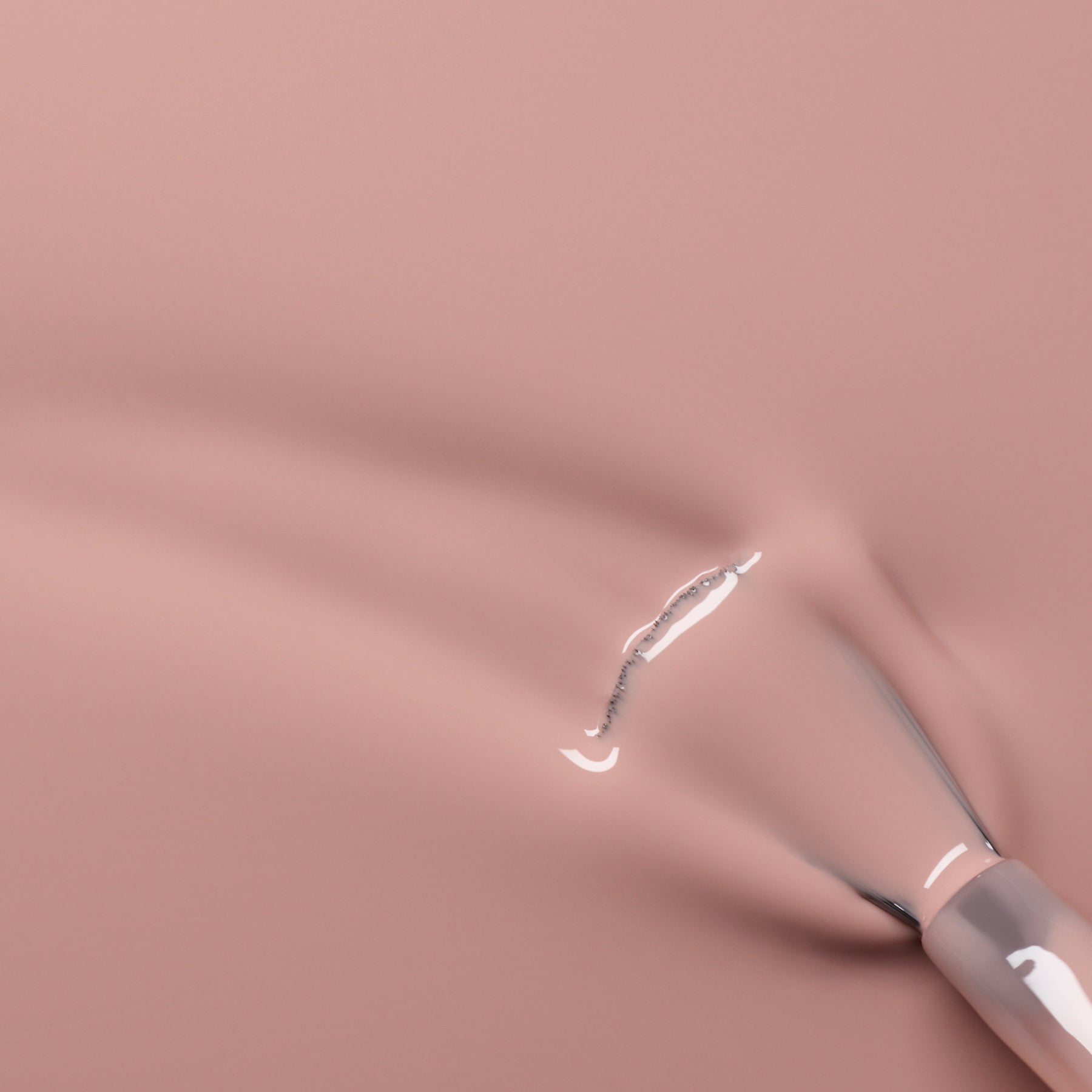 A close-up of a nail polish brush spreading glossy, nude-pink nail polish on a smooth surface.