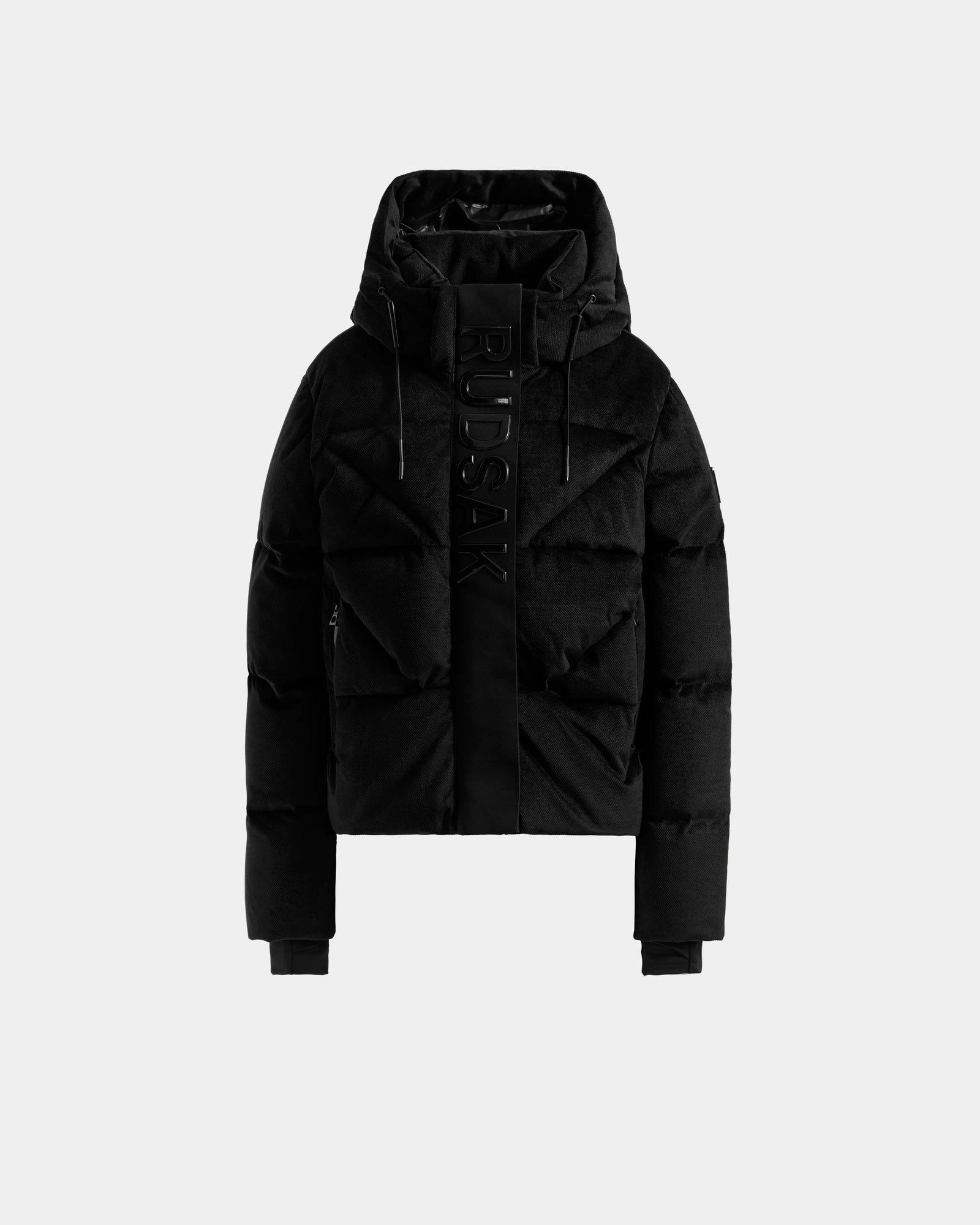 The STEFANIE V - L125584 Black by Rudsak is a black down puffer winter jacket with a hood, front zipper, ribbed cuffs, and "RUDSAK" vertically on the front, shown against a plain light grey background.