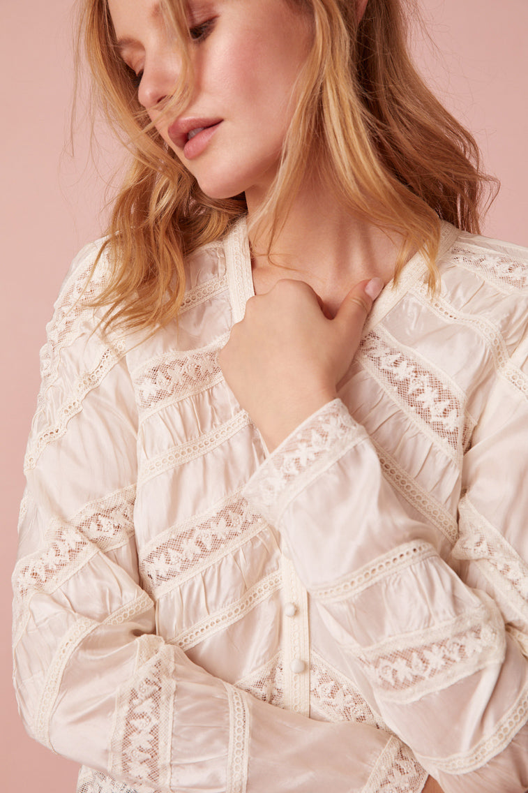 Long sleeve button down top with a v-neckline and diagonal laces for added texture detailing.