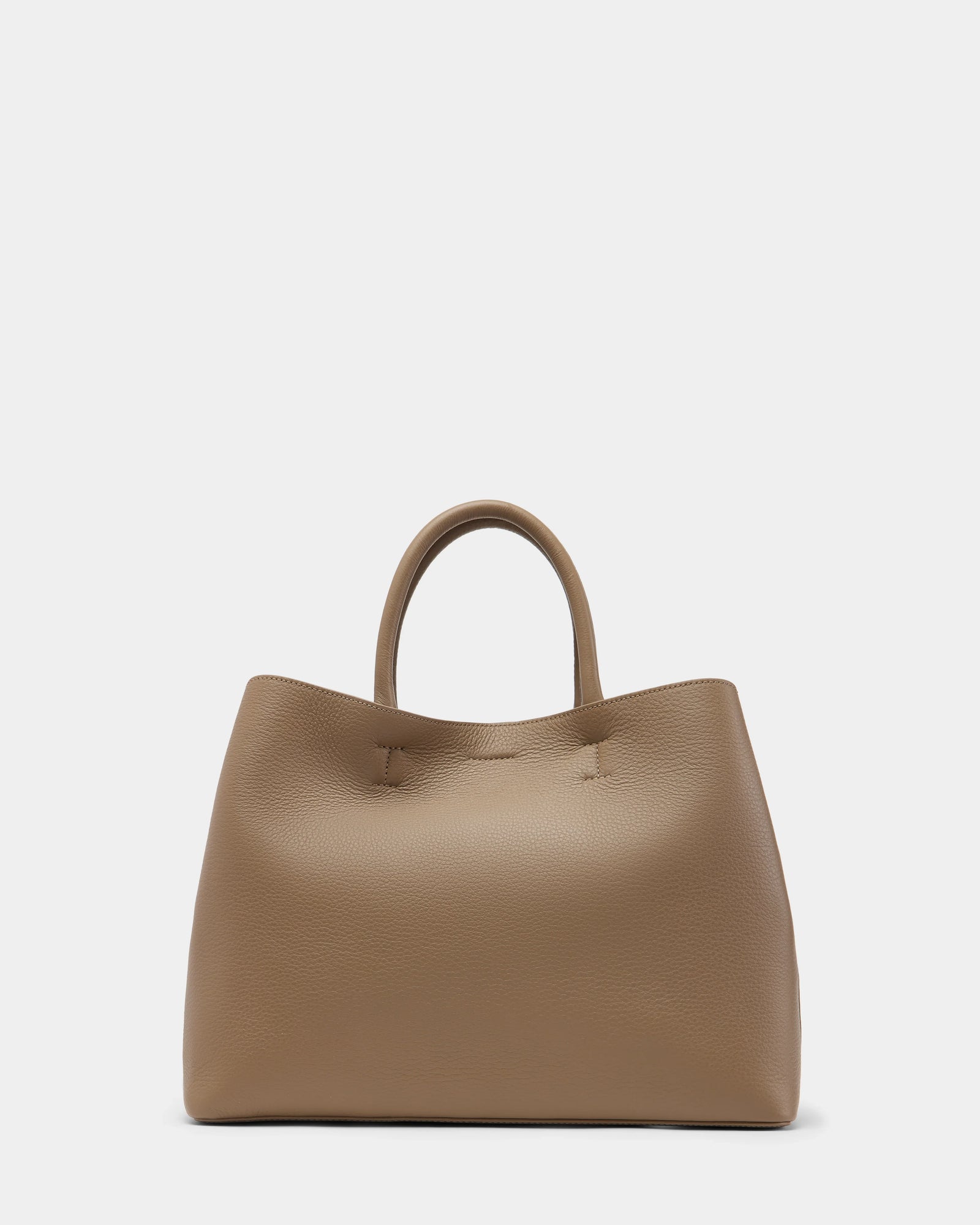 The Rudsak CATIRA L - 8325007 Almond is a taupe pebble leather tote with a textured finish, two short handles, and a minimalist, slightly slouchy design, shown against a plain white background.
