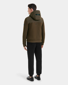 A man stands facing away, wearing the Rudsak DEE MAT - 6124028 Army lightweight hybrid down jacket in olive green, black pants, and black sneakers against a plain white background.