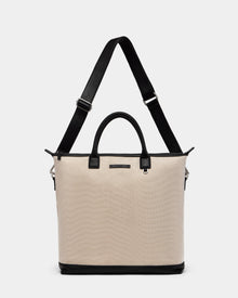 The Rudsak DEXTER - 9324513 Vanilla is a unisex beige canvas tote with black leather handles, a black base, and an adjustable shoulder strap, shown against a plain white background.