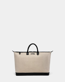 The Rudsak DUBLIN - 9324514 Vanilla is a large beige canvas leather unisex weekender tote with black handles and trim, featuring a structured, minimalist design. It’s showcased on a plain light gray background.