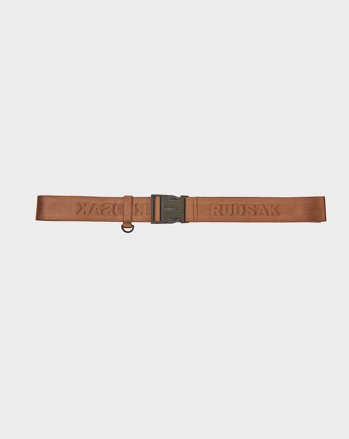 The AVAN FINAL SALE - 9422023 COHIBA by Rudsak is a brown adjustable unisex belt with an embossed RUDSAK logo, black matte hardware, and a small metal ring attachment, shown on a plain white background.
