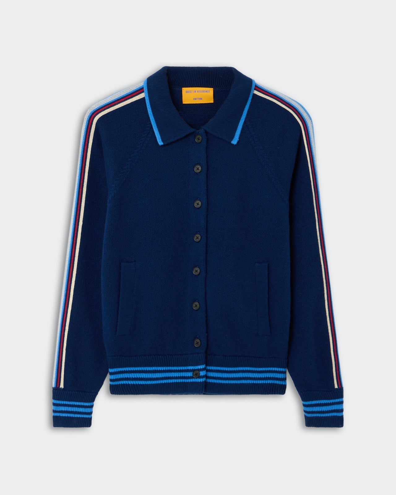 Varsity Jacket - Navy, a deep navy knit jacket with button-down front, featuring contrasting light blue, red, and cream stripes running along the shoulders and sleeves, ribbed collar, cuffs, and hem, and front pockets.