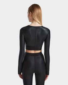 A woman with straight, light brown hair stands facing away, wearing the Rudsak LORA - 8524026 Black fitted long sleeve top and matching high-waisted leggings against a plain white background.
